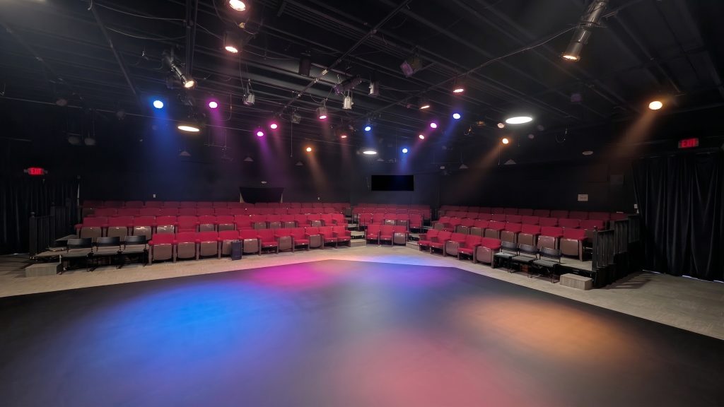 The beautifully lit stage and red stadium seating at Stage Door Theatre, the perfect venue for Surya Ensemble's immersive live music Atlanta performances.